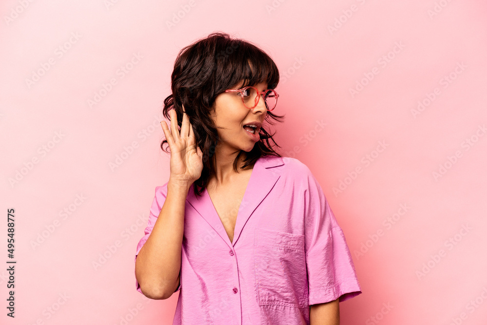 Young hispanic woman isolated on pink background trying to listening a gossip. Young hispanic woman isolated on pink background trying to listening a gossip.