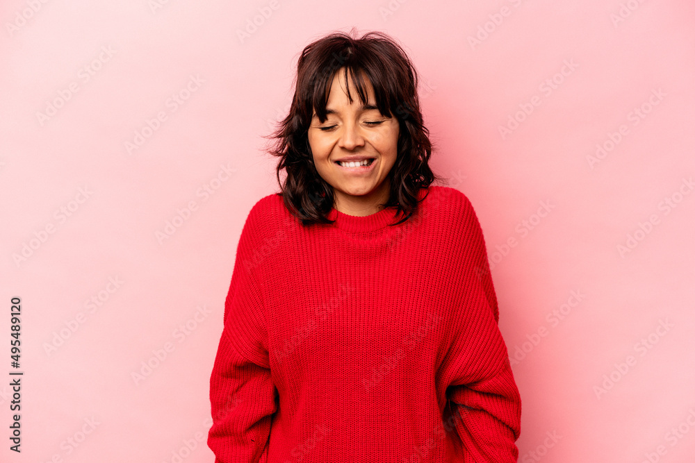 Young hispanic woman isolated on pink background laughs and closes eyes, feels relaxed and happy.