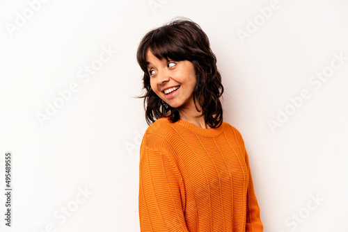 Young hispanic woman isolated on white background looks aside smiling, cheerful and pleasant.