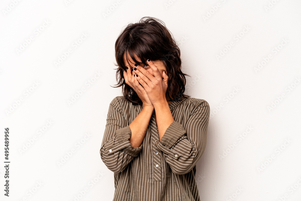 Young hispanic woman isolated on white background blink at the camera through fingers, embarrassed covering face. Young hispanic woman isolated on white background blink at the camera through fingers, embarrassed covering face.