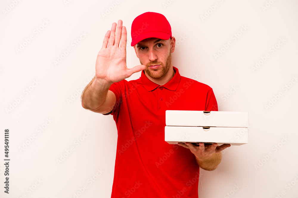 Young delivery caucasian man holding pizzas isolated on white background standing with outstretched hand showing stop sign, preventing you. Young delivery caucasian man holding pizzas isolated on white background standing with outstretched hand showing stop sign, preventing you.