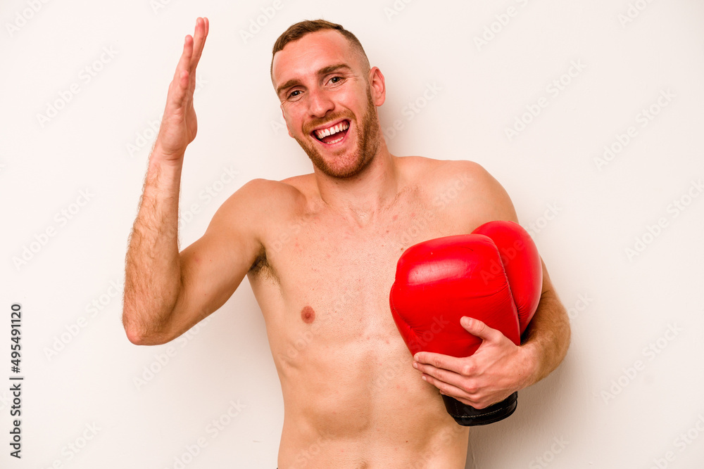 Young caucasian man doing boxing isolated on white background receiving a pleasant surprise, excited and raising hands.