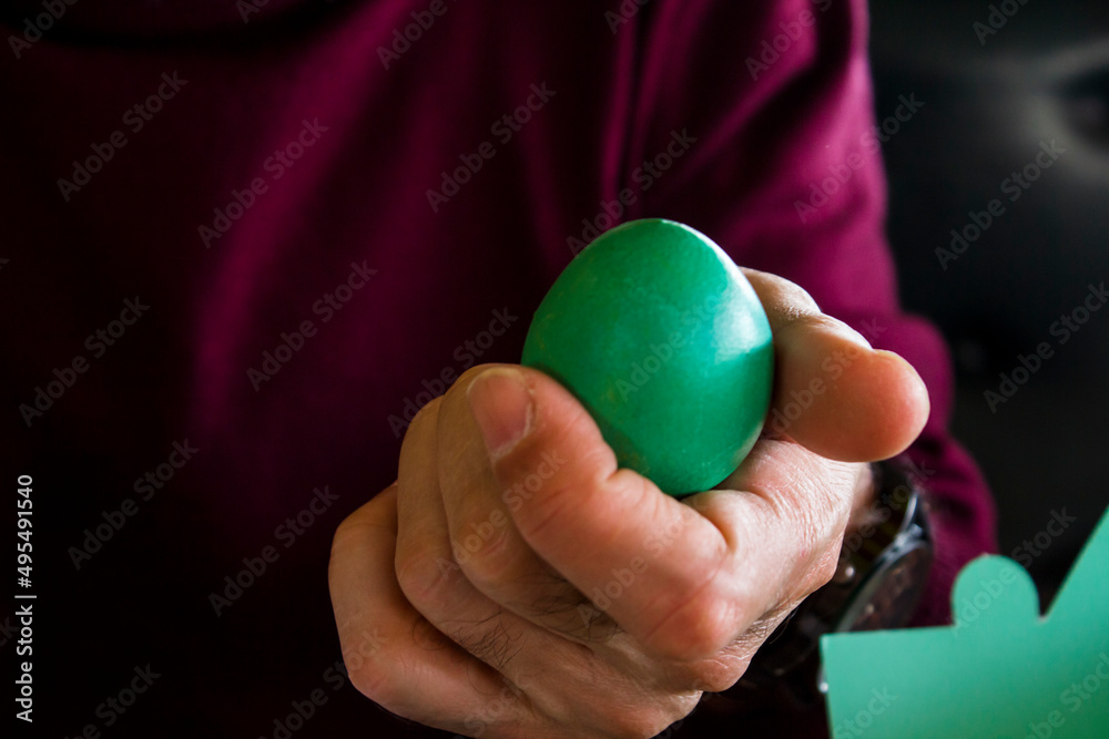 Hand of adult,unknown man holding green colored Easter Egg.Close up taken. Hand of adult,unknown man holding green colored Easter Egg.Close up taken.
