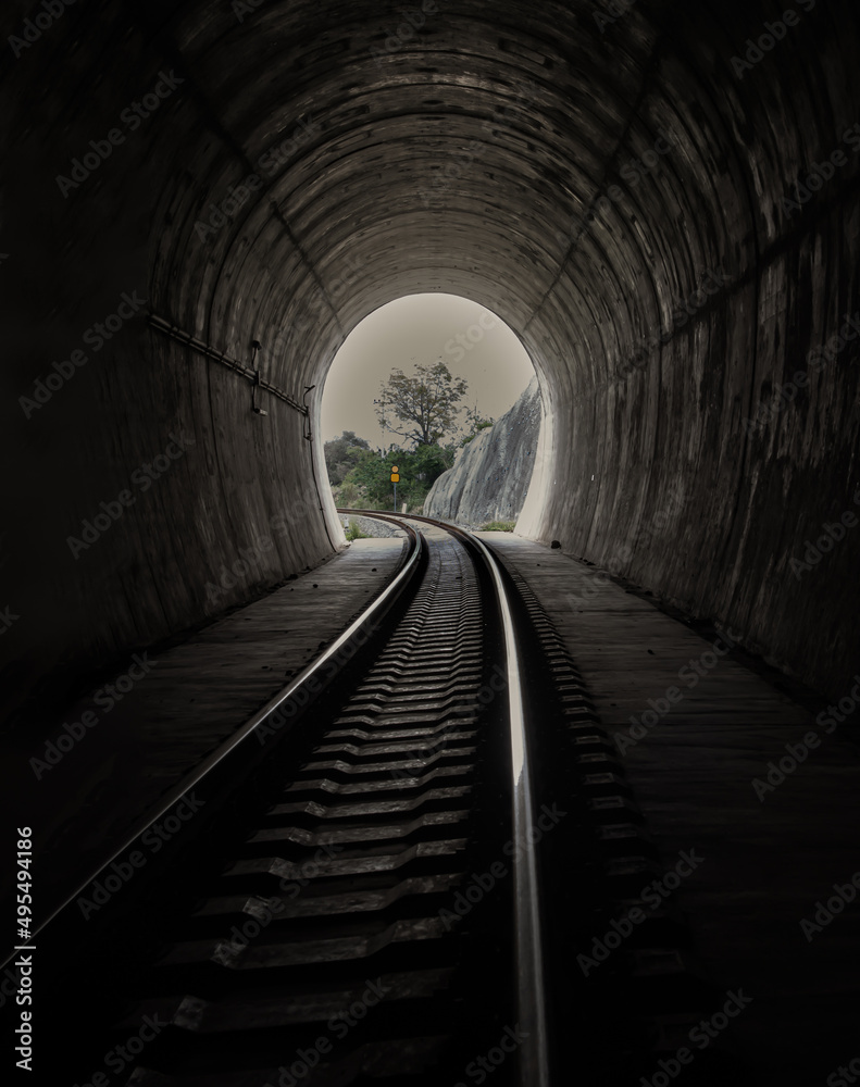 Inside the railroad tunnel and railways with natural light at the end. Light at the end of the tunnel, Lights and shadows, Concept of achieving your goals, Copy space, Selective focus. Inside the railroad tunnel and railways with natural light at the end. Light at the end of the tunnel, Lights and shadows, Concept of achieving your goals, Copy space, Selective focus.