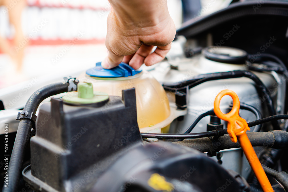 man opening a cup where the coolant for the car is stored