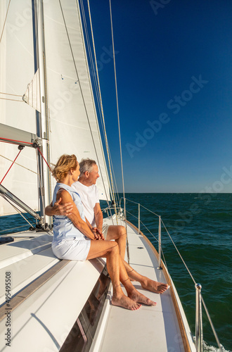 Loving retired couple sailing yacht towards distant horizon