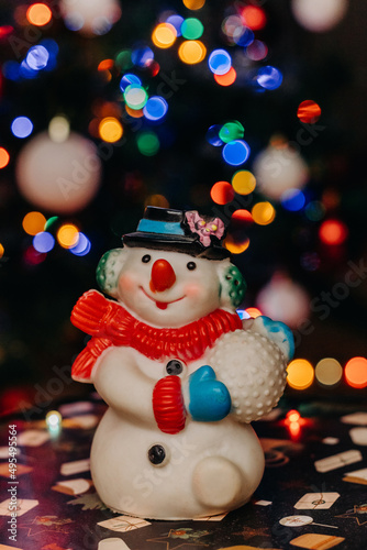 Toy  snowman on the background of festive Christmas lights.  Snowman figurine. bokeh. Christmas. New Year