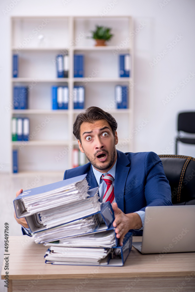 Obraz premium Young male employee and too much work in the office