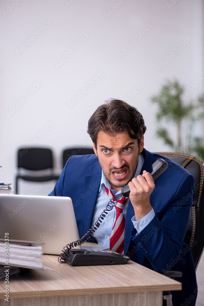 Young male employee and too much work in the office Young male employee and too much work in the office