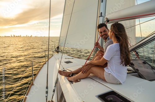Smiling Latin American couple sailing yacht at sunrise