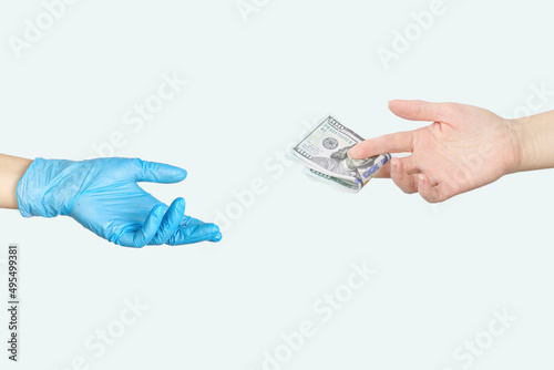Hand handing over money to another hand in blue medical glove on white background.