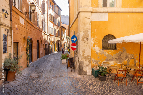 Fototapeta Naklejka Na Ścianę i Meble -  Narrow street with cafe and small shops in Rome. Italy travel concept, visiting cozy places