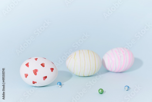 Close-up of three Easter eggs with a pattern of hearts and lines on a blue background with decor. Side view with space to copy. High quality photo