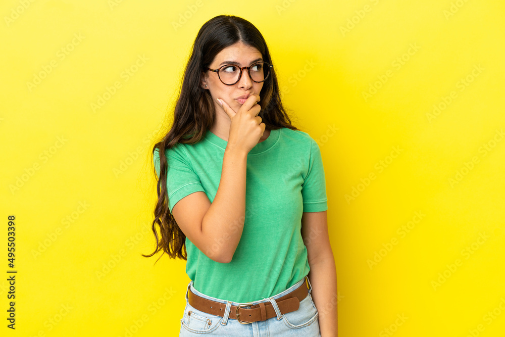Young caucasian woman isolated on yellow background having doubts and with confuse face expression Young caucasian woman isolated on yellow background having doubts and with confuse face expression