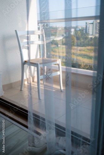 on an open minimalistic balcony overlooking the sea, there is an empty chair