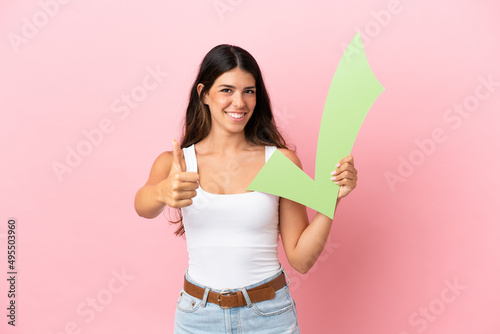 Tableau sur toile Young caucasian woman isolated on pink background holding a check icon with thum