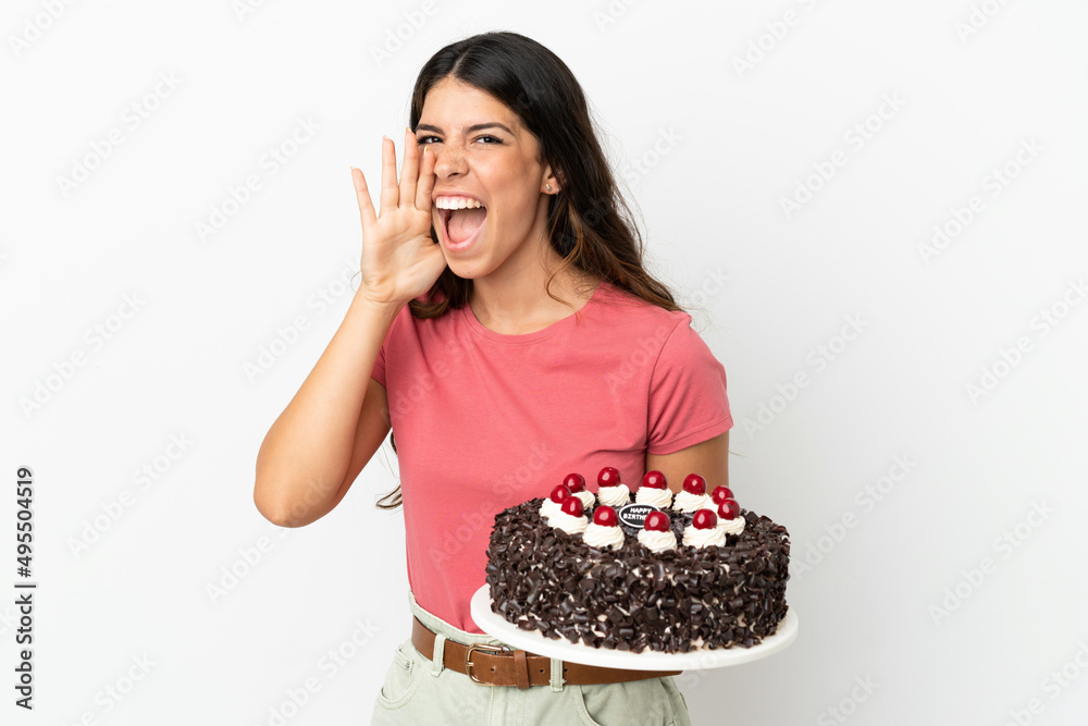 Young caucasian woman holding birthday cake isolated on white background shouting with mouth wide open Young caucasian woman holding birthday cake isolated on white background shouting with mouth wide open
