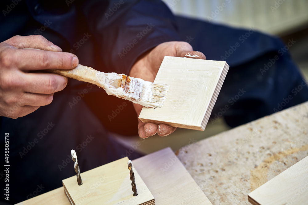 The carpenter works with wooden parts, gluing, grinding elements, work in the workshop