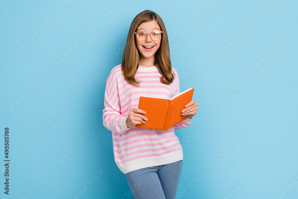 Portrait of positive cheerful girl hold book beaming smile look camera isolated on blue color background Portrait of positive cheerful girl hold book beaming smile look camera isolated on blue color background