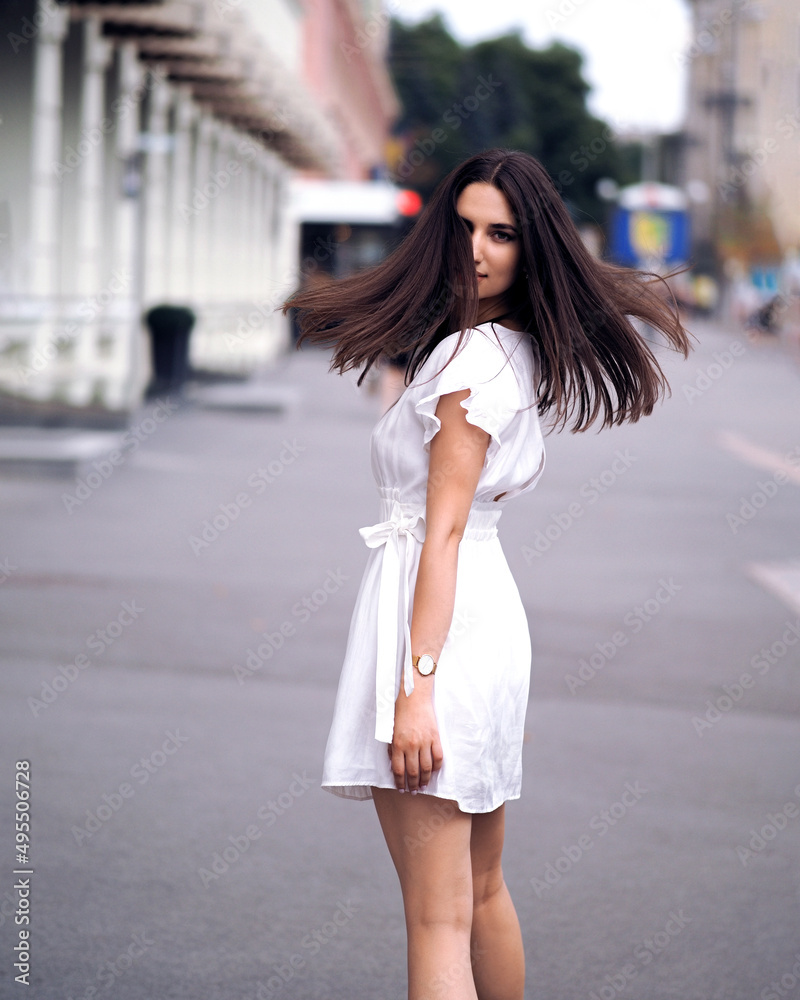 Brunette woman in white dress in the city