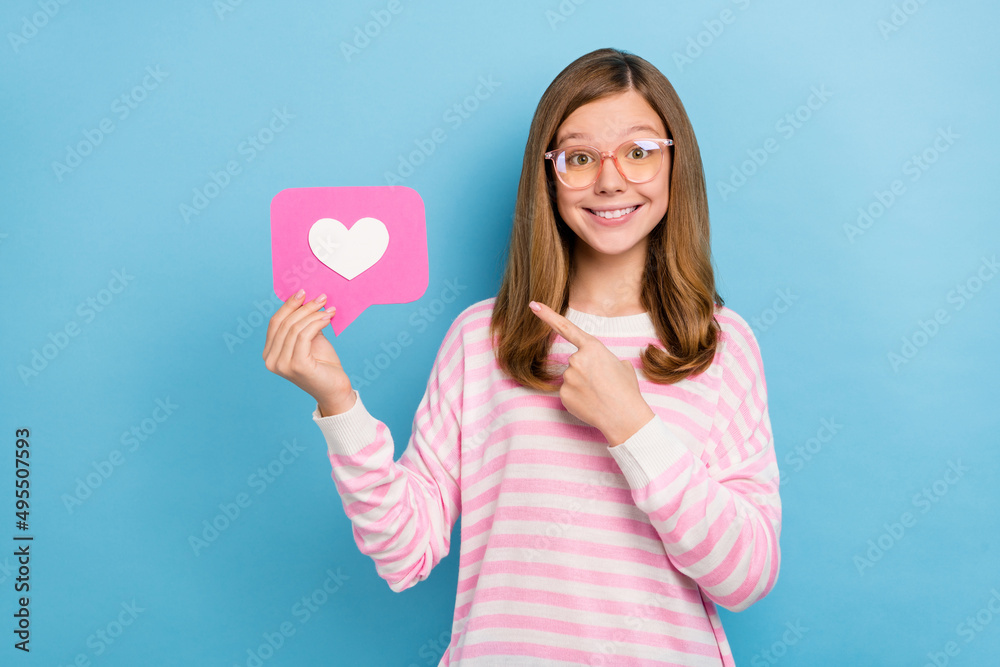 Portrait of charming schoolgirl indicate finger paper like card isolated on blue color background