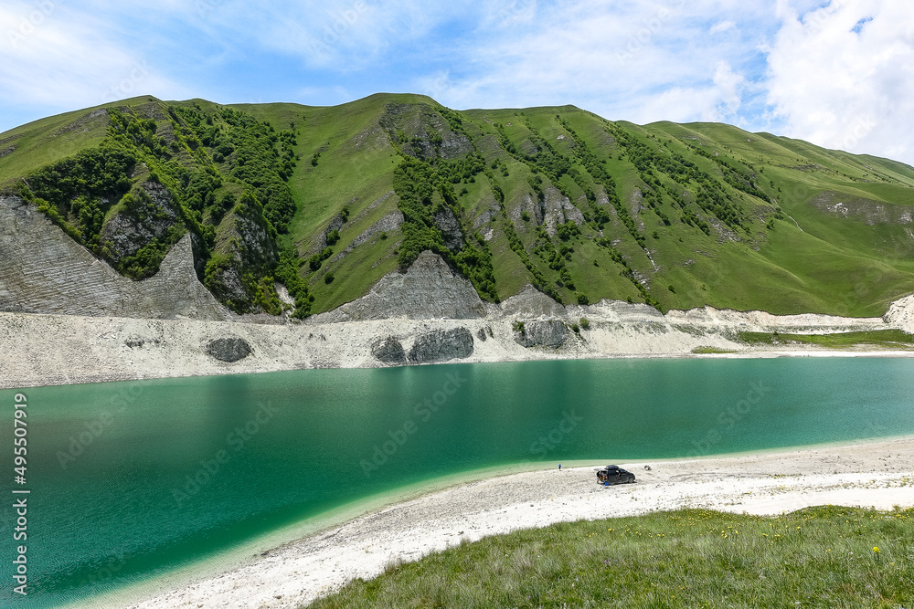 A car on the background of Lake Kezenoy-am in the Caucasus mountains in Chechnya, Russia, June 2021.