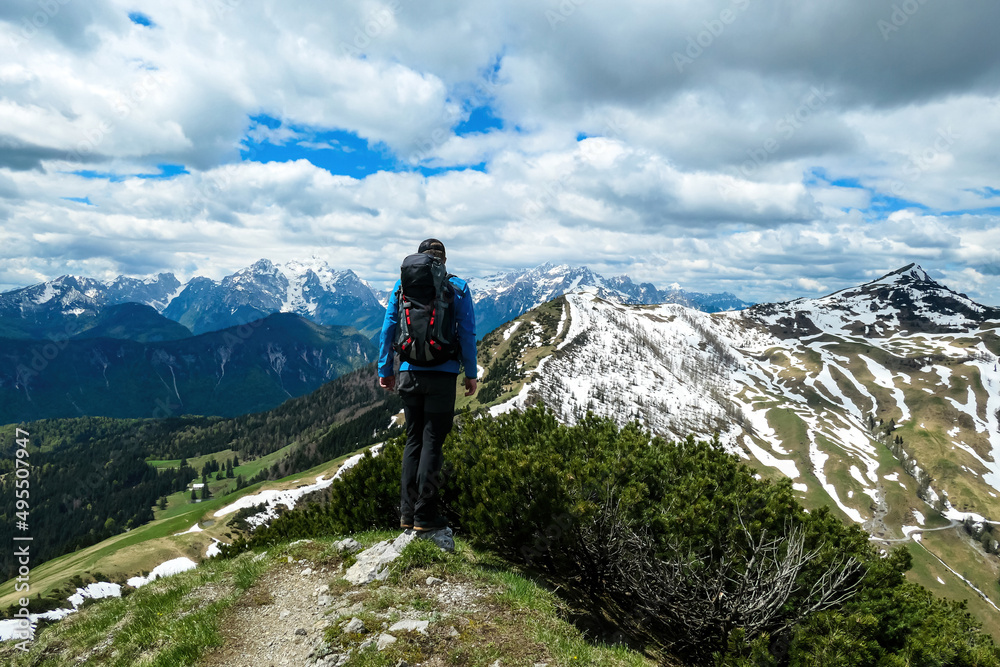 Hiker man breathing on the summit of Hahnkogel (Klek) with scenic view on mountain peaks in the Karawanks and Julian Alps, Carinthia, Austria. Border with Slovenia. Triglav National Park. Freedom