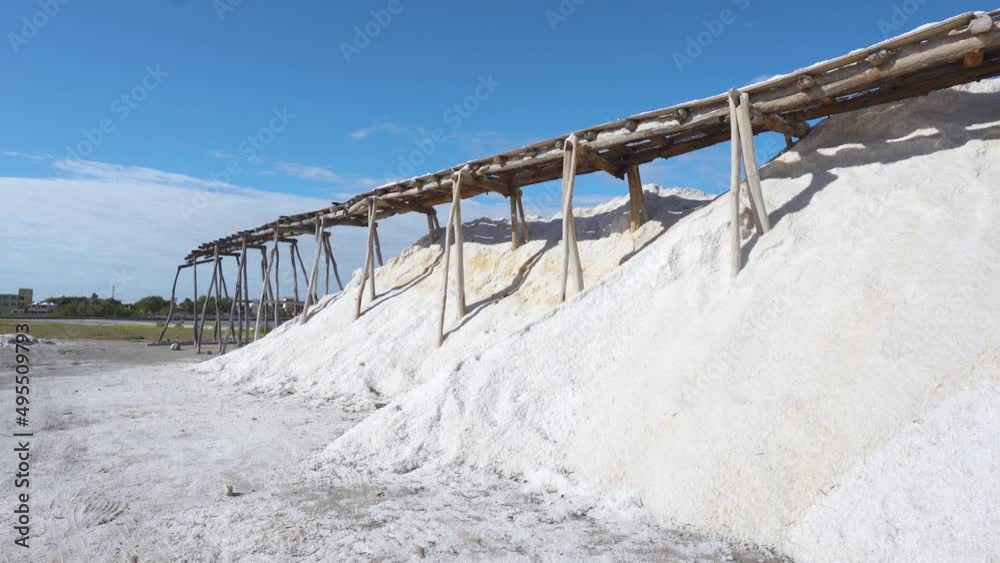 Mountains of sea salt on a tropical peninsula in the Dominican Republic. Extraction of table salt by garden method. Wooden supports under the railroad yf against the sky. Mountains of sea salt on a tropical peninsula in the Dominican Republic. Extraction of table salt by garden method. Wooden supports under the railroad yf against the sky.