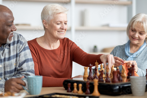 Attarctive senior woman playing chess with multiracial friends photo