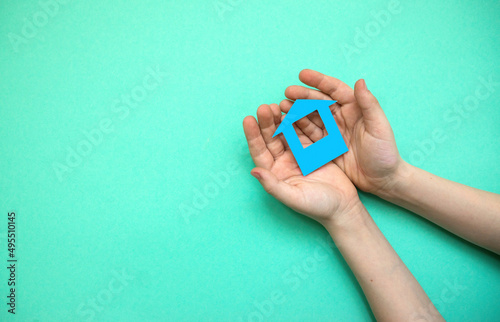 The child's hands hold a house cut out of paper. The concept of buying a house. Home insurance theme. Copyspice on the left. House in the hands of a child photo