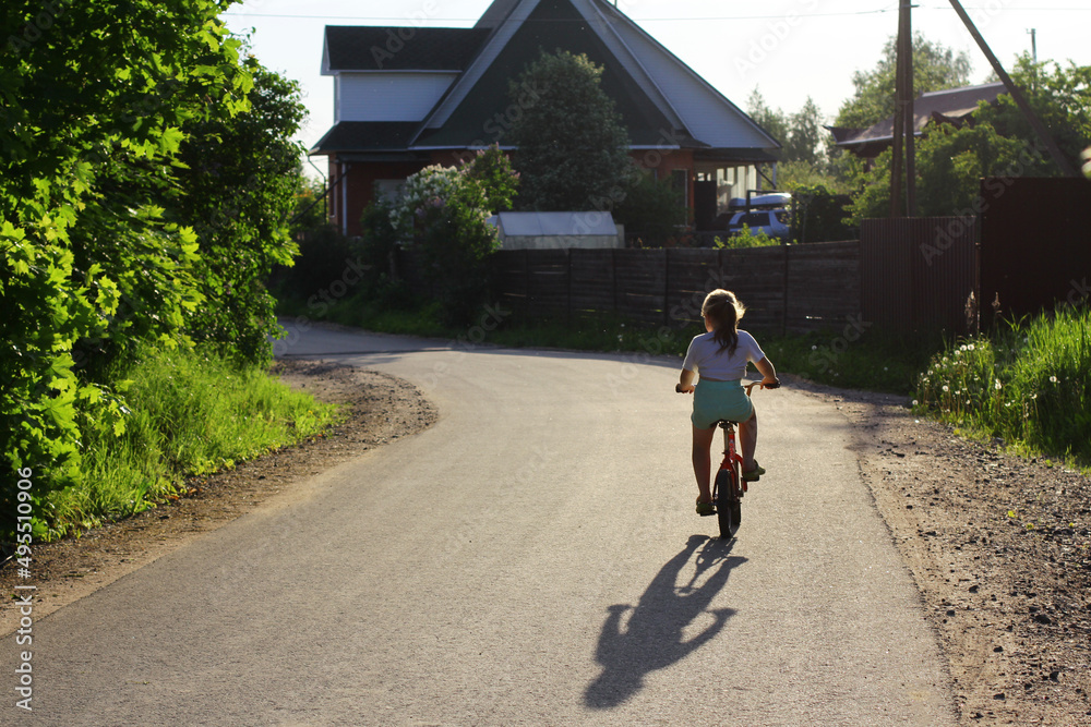 The lifestyle of the suburbs. Girl rides a Bicycle in the sunset light