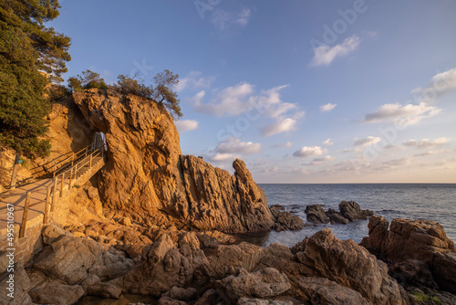 Walkway with wooden handrails along the coast. Evening seascape. Rocks in the foreground.