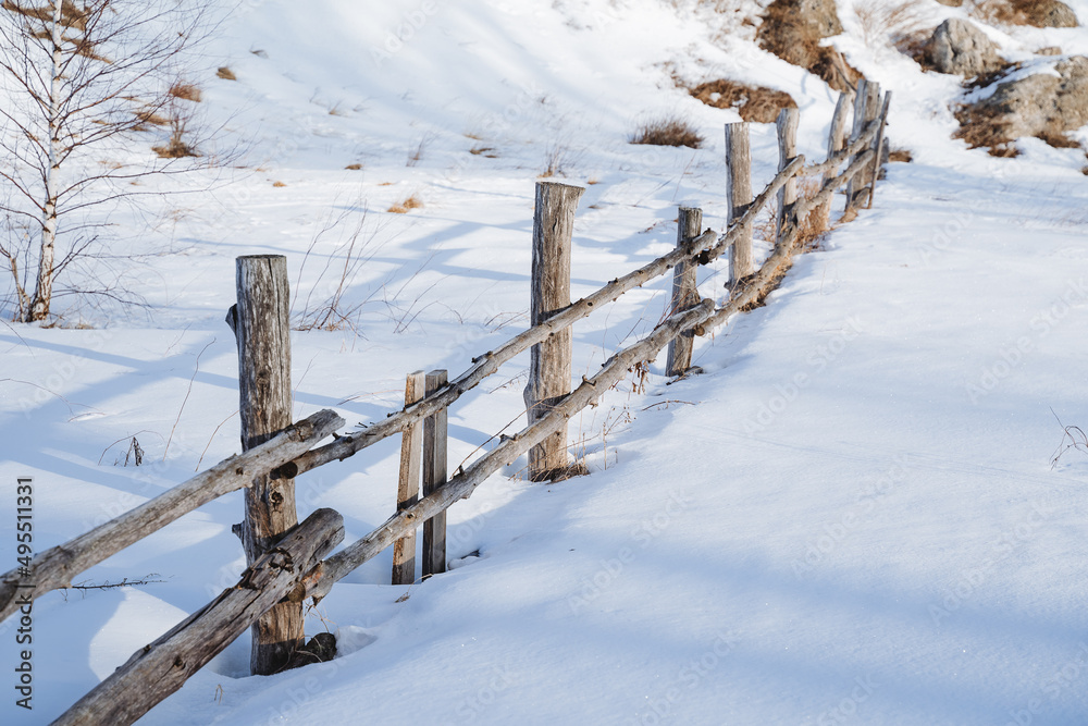 Wooden fence in winter under the snow, corral for livestock, fencing on the ranch for animals. winter landscape. A barrier made of logs of old trees. Wooden fence in winter under the snow, corral for livestock, fencing on the ranch for animals. winter landscape. A barrier made of logs of old trees.