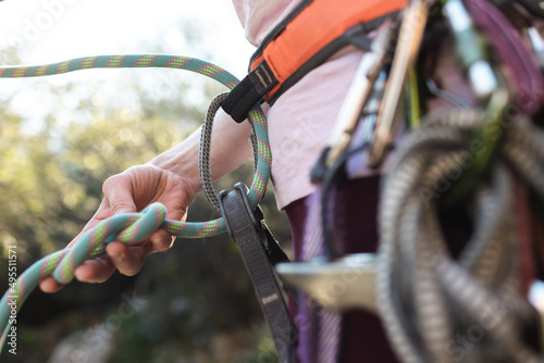 A rock climber prepares equipment for climbing, woman holds a rope, knot