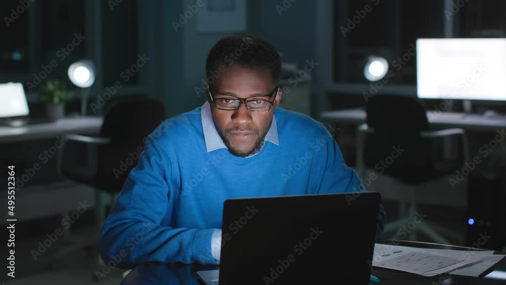 African-American manager in glasses read email on laptop working late in evening