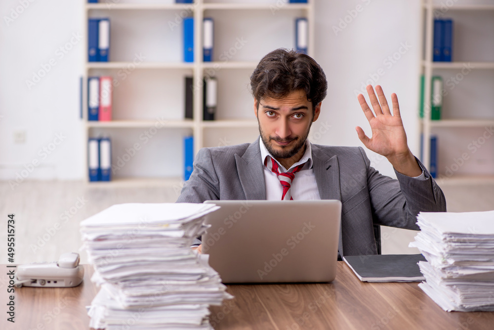 Young male employee unhappy with excessive work in the office Young male employee unhappy with excessive work in the office