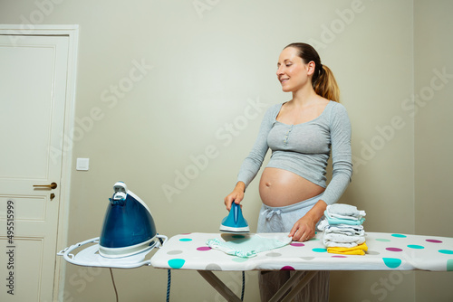 Pregnant woman with big belly iron newborn baby clothes