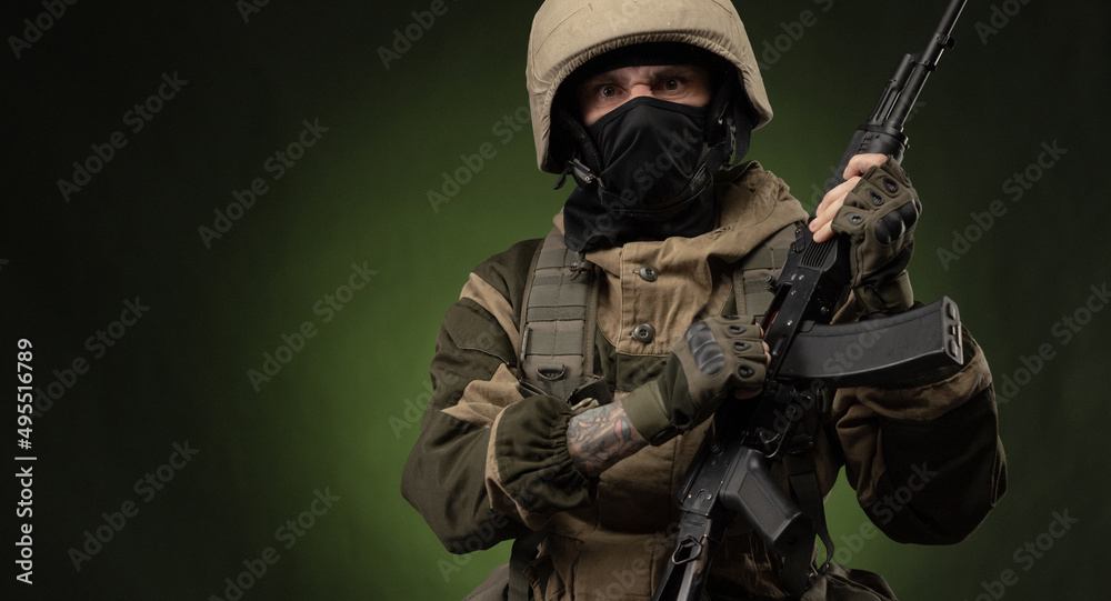 a Russian soldier in a helmet in military clothes with a Kalashnikov assault rifle on a dark background in the studio