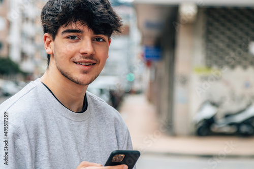 portrait of millennial teenager with mobile phone in the street