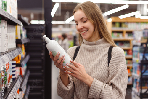 Obraz na płótnie Positive young blonde selecting bottle of shampoo in cosmetics department store w salonie