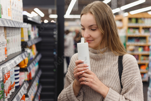 Shopping cosmetics - woman smelling bottle of shampoo in store