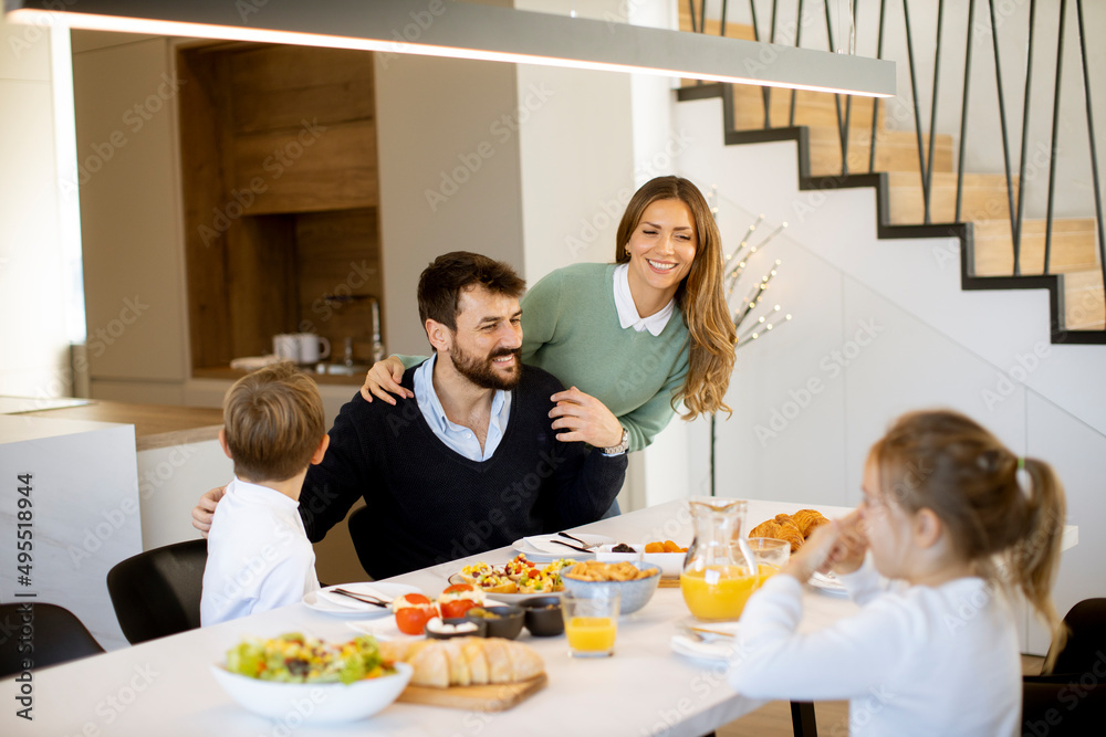 Young happy family talking while having breakfast at dining table