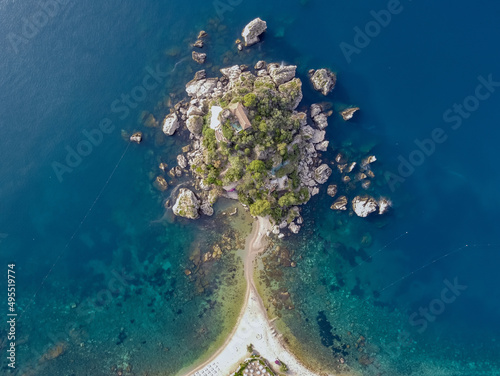 Aerial drone. Isola Bella small island in Taormina, Sicily, Italy. A small sand strip connects to the beach surrounded by turquoise Ionian sea water. © Roberto