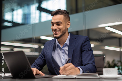 Happy arabic entrepreneur surfing on Internet, office interior