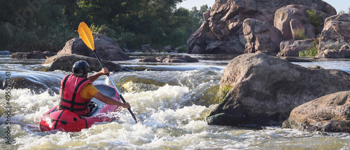 A man rowing inflatable packraft on whitewater of mountain river. Concept: summer extreme water sport, active rest, extreme rafting. © Oleksandra