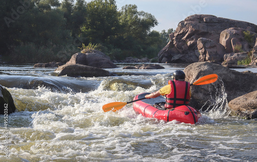 A man rowing inflatable packraft on whitewater of mountain river. Concept: summer extreme water sport, active rest, extreme rafting. © Oleksandra