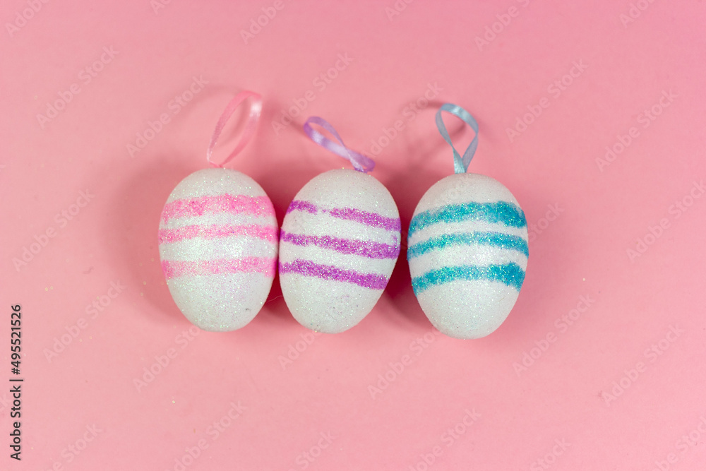 Three Easter eggs of different colors on a pink background. Abstract Easter background. A copy of the space Three Easter eggs of different colors on a pink background. Abstract Easter background. A copy of the space
