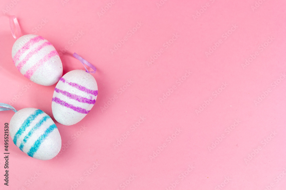 Fototapeta premium Three Easter eggs of different colors on a pink background. Abstract Easter background. A copy of the space