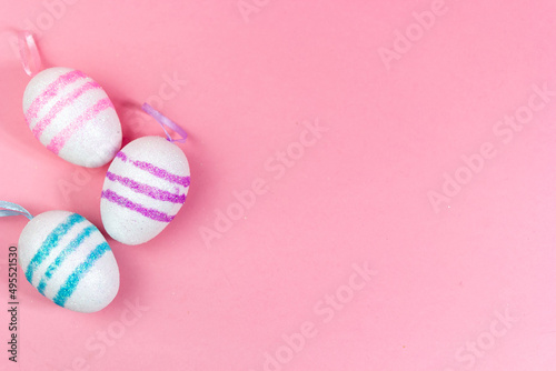 Three Easter eggs of different colors on a pink background. Abstract Easter background. A copy of the space