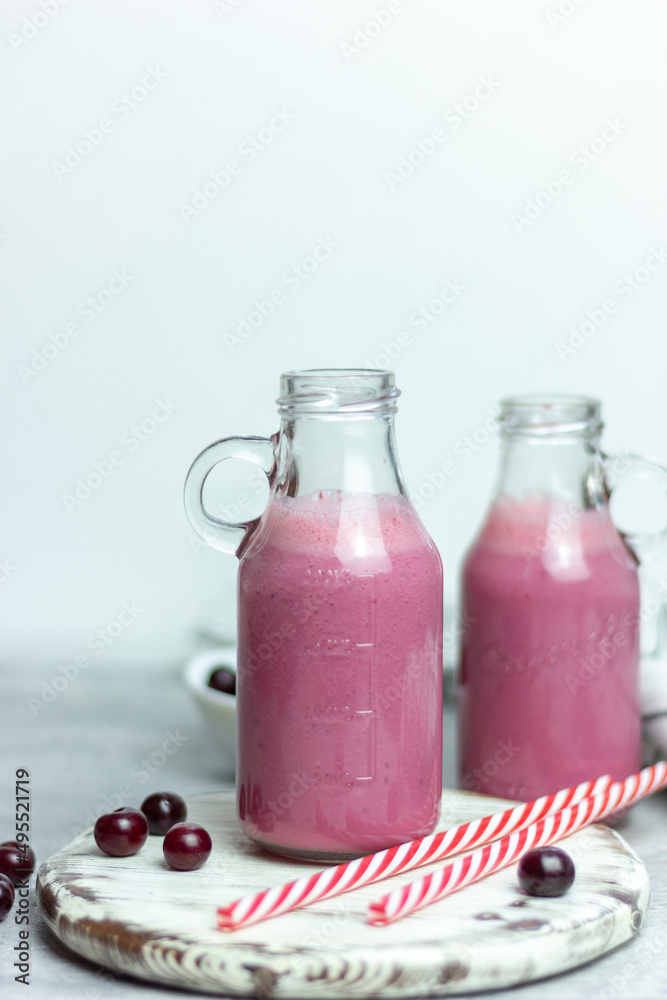 A bottle of cherry smoothies on a white background, cherries in bulk and in a plate. Morning summer breakfast A bottle of cherry smoothies on a white background, cherries in bulk and in a plate. Morning summer breakfast